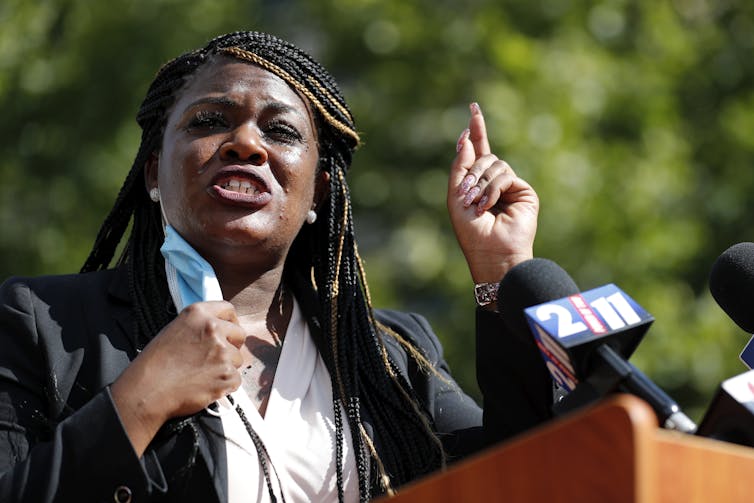 A woman gestures from behind a podium.