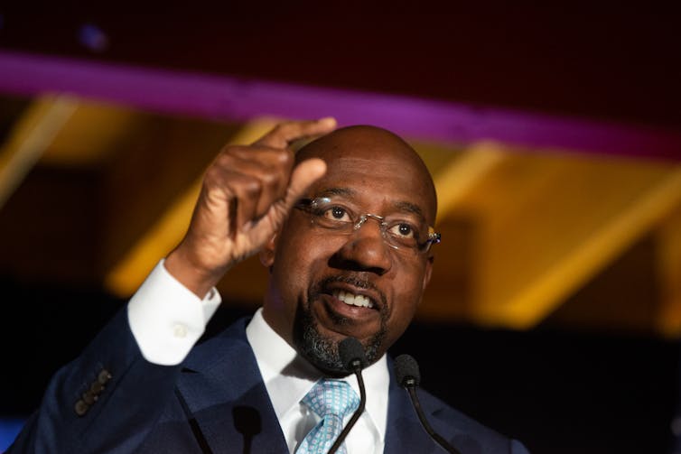 Raphael Warnock points as he speaks during an Election Night event.