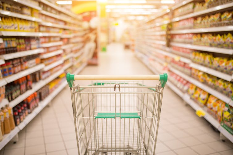 Empty shopping trolley in supermarket aisle.