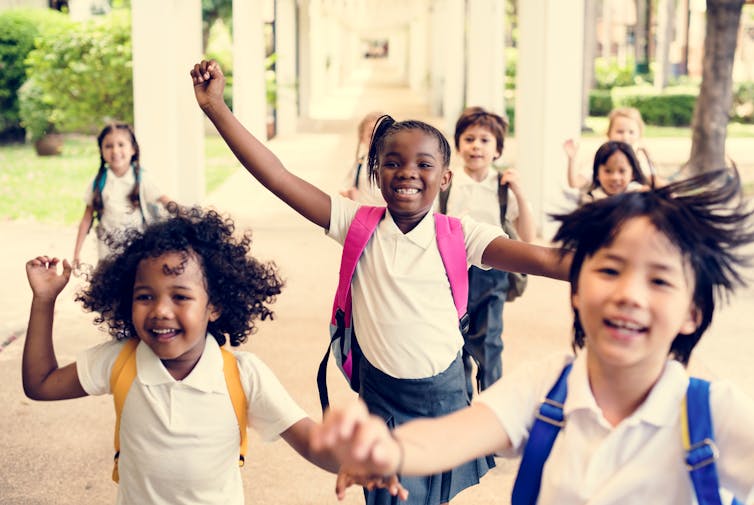 A group of children run around at school.