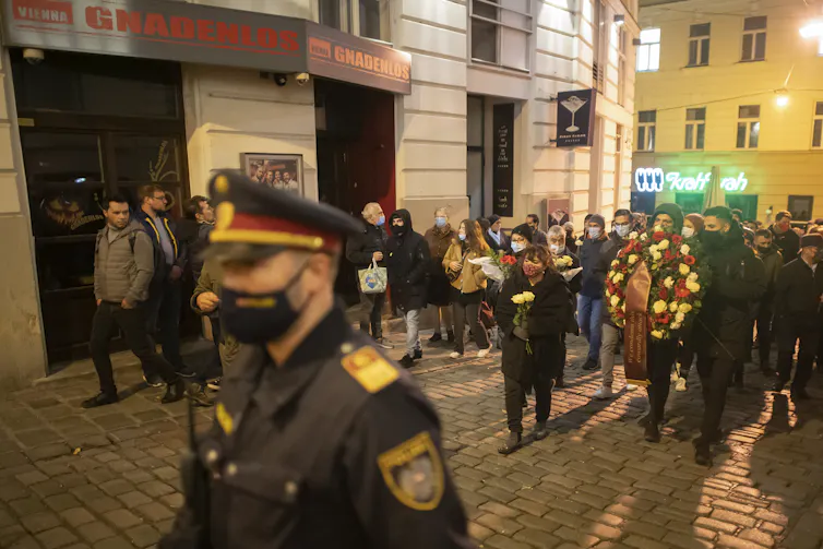 People bring flowers to the site of a terrorist attack in Vienna.