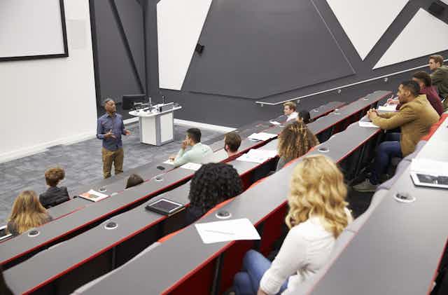 Students listen to lecturer in a half-empty lecture theatre