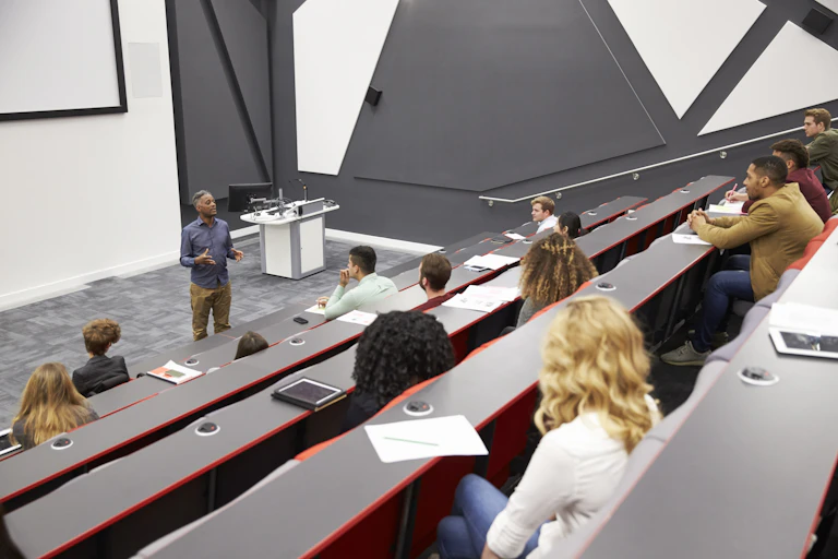 Students listen to lecturer in a half-empty lecture theatre