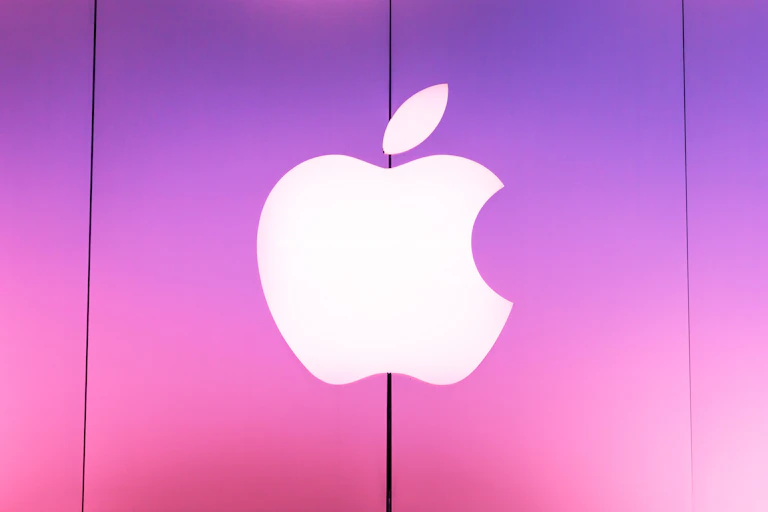 The Apple corporate sign outside a store lit up in pink.