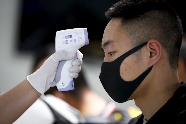 A man having his temperature checked at an airport.