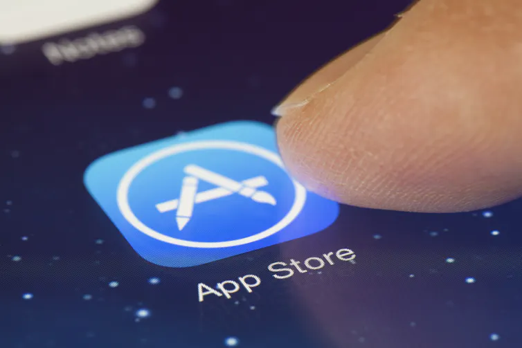 Apple's App Store button on an iPhone with a finger hovering above it.