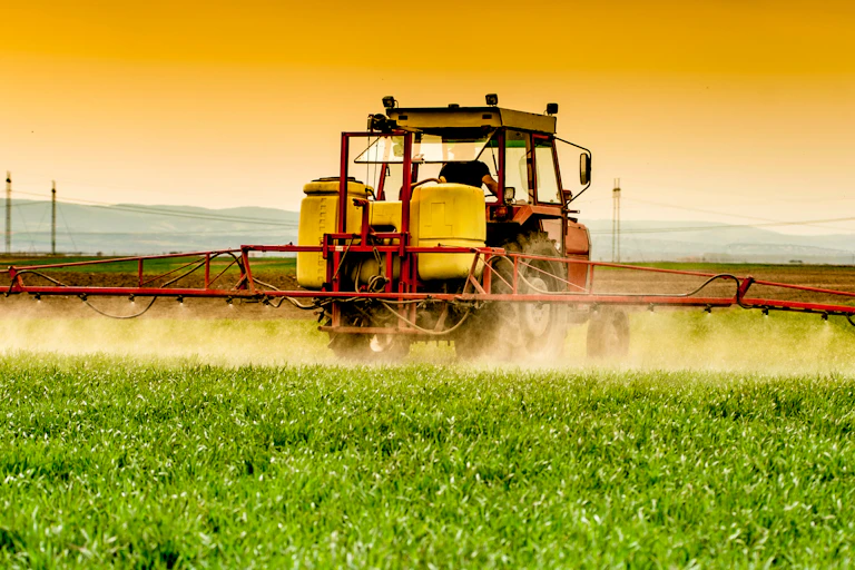 A tractor spraying a wheat field.