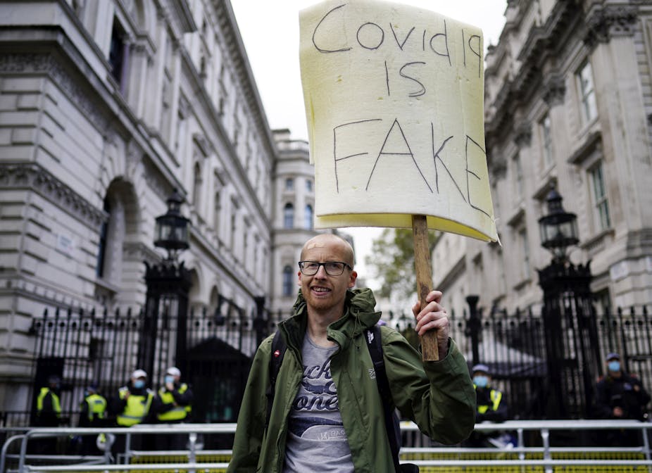 A protester holding a placard that says "COVID-19 is fake"