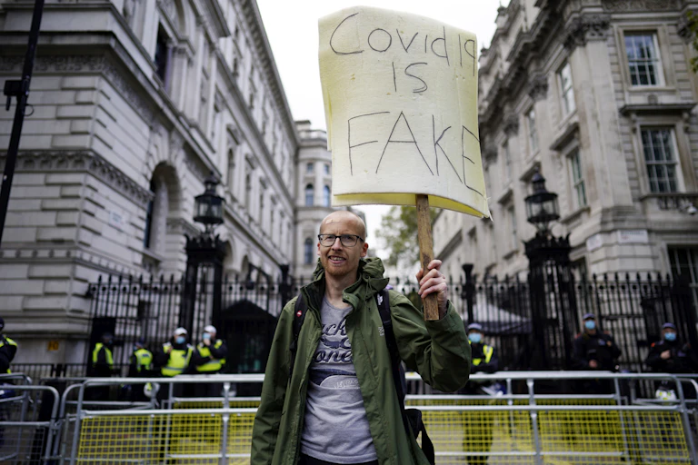 A protester holding a placard that says "COVID-19 is fake"
