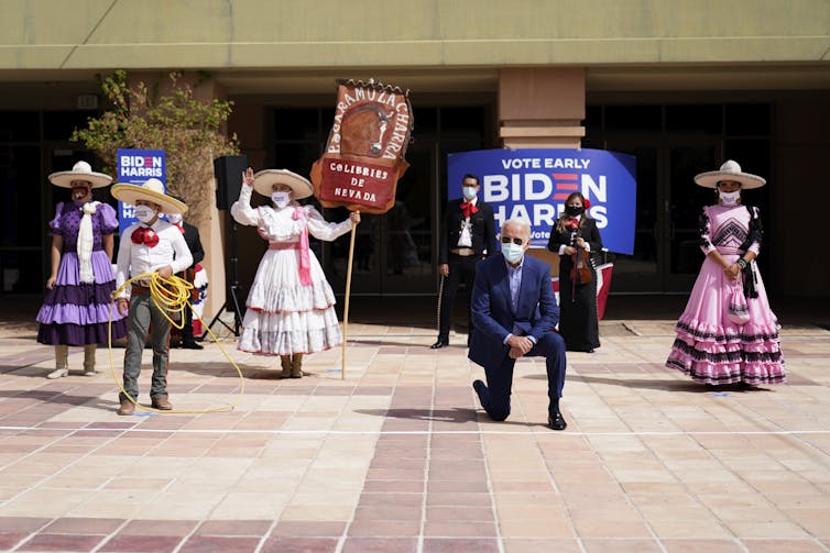 Joe Biden takes a knee in front of five performers in costume