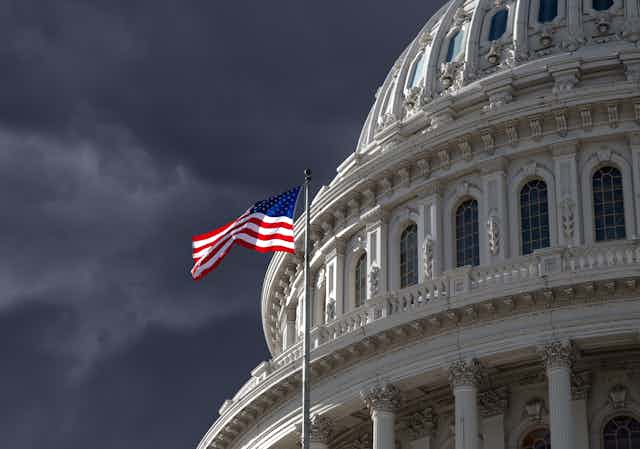 Flag flies at the US capitol, stormy sky