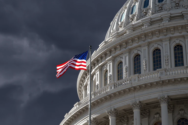 Flag flies at the US capitol, stormy sky