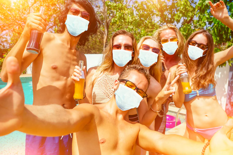 Jóvenes en bañador y con mascarilla con ambiente festivo.