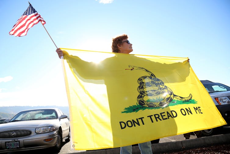 A woman holds the Gadsden flag