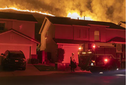 Fire burns on ridge behind homes