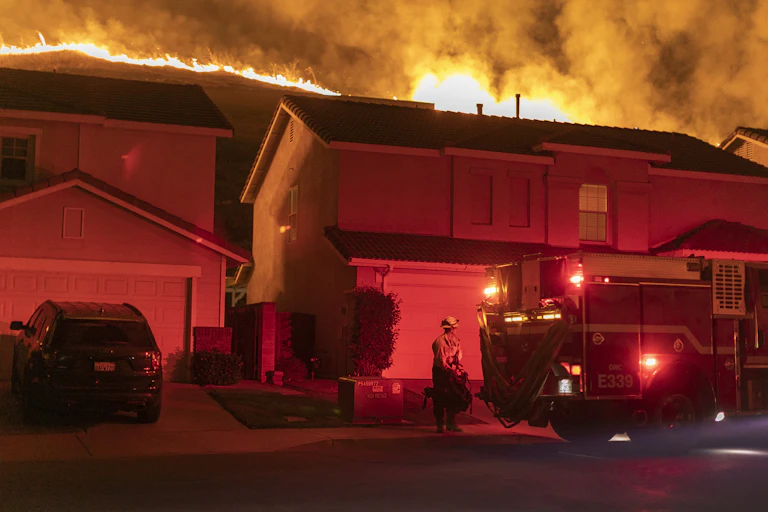 Fire burns on ridge behind homes