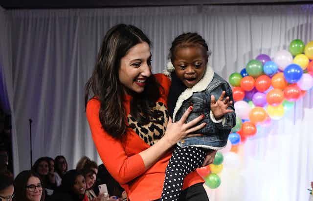 A woman holding a child with cancer at a fundraising event.