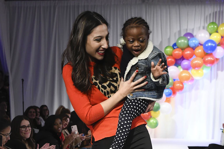 A woman holding a child with cancer at a fundraising event.