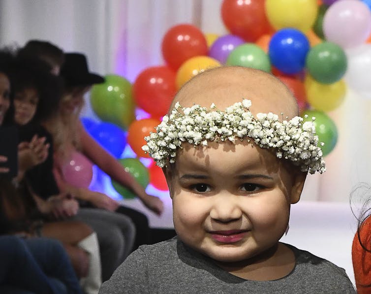 A little girl who has cancer with no hair but a crown of flowers.