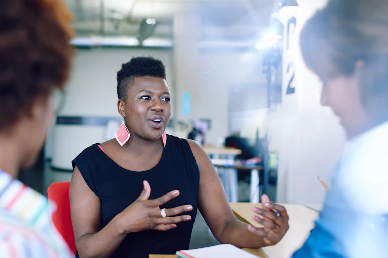 A woman gestures in a meeting at work.