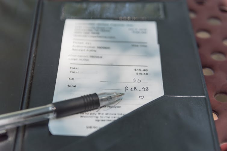 A signed credit card receipt on a restaurant table