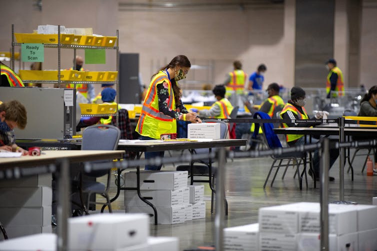 Woman standing behind a table counting votes.