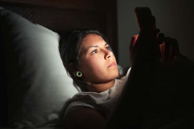 woman on her phone in bed in dark