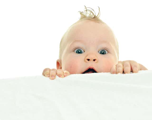 Un bebé asoma la cabeza tras una sábana.
