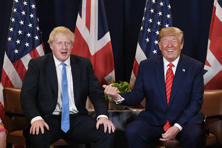 Boris Johnson and Donald Trump sat smiling in front of US and UK flags.