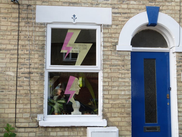 A lightning bolt sign in the window of a terraced house.