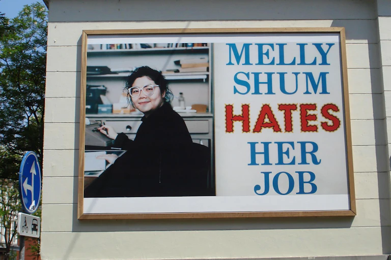 A woman smiling in glasses on a billboard.