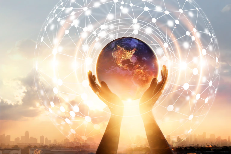 A pair of hands holding a globe of the Earth in front of a sunrise, with an abstract network diagram superimposed.