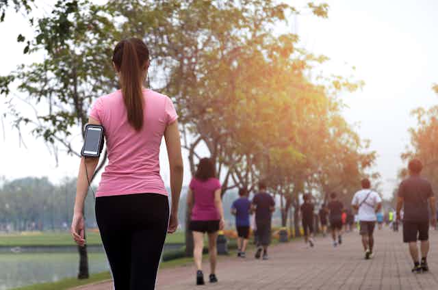 A woman wearing a smartphone goes walking.