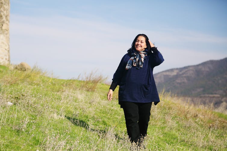 A woman goes walking in a field.