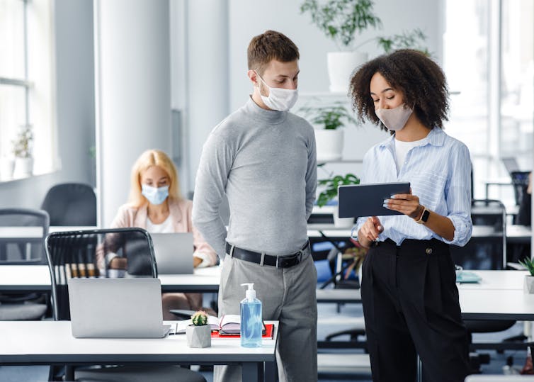 A woman and man talk at work while looking at an iPad.