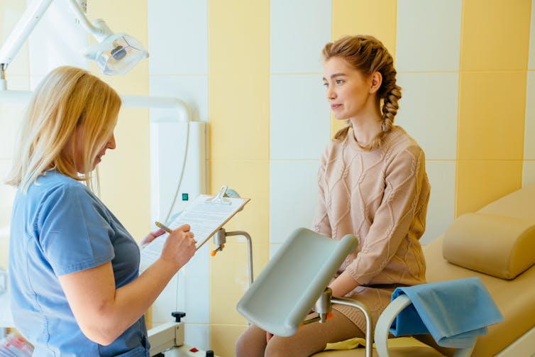 Women sitting on bed speaking with a doctor.