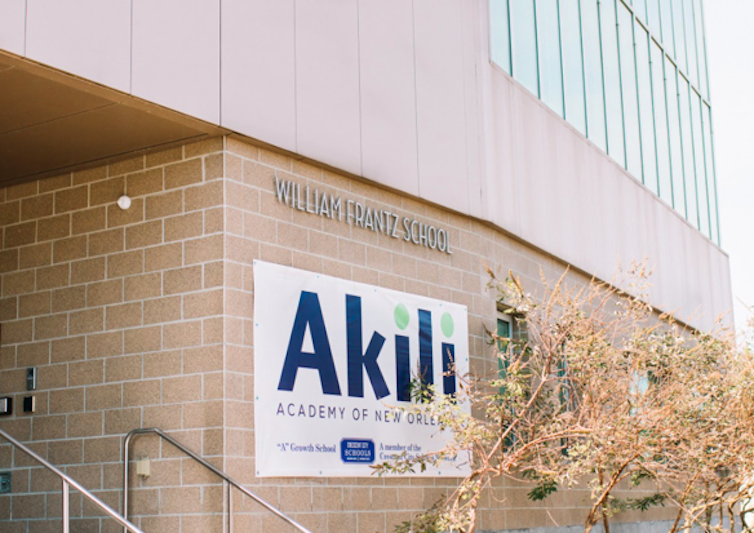 A sign saying Akili Academy on a beige brick building