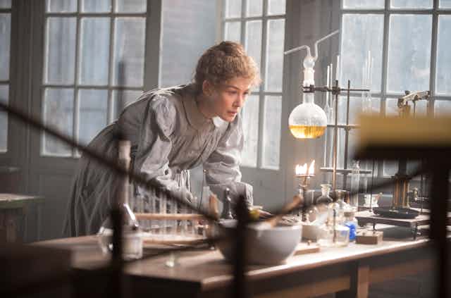 Marie Curie looks at a science experiment