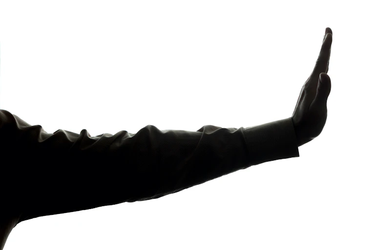 Arm stretched and hand held up indicating a person to stop talking.