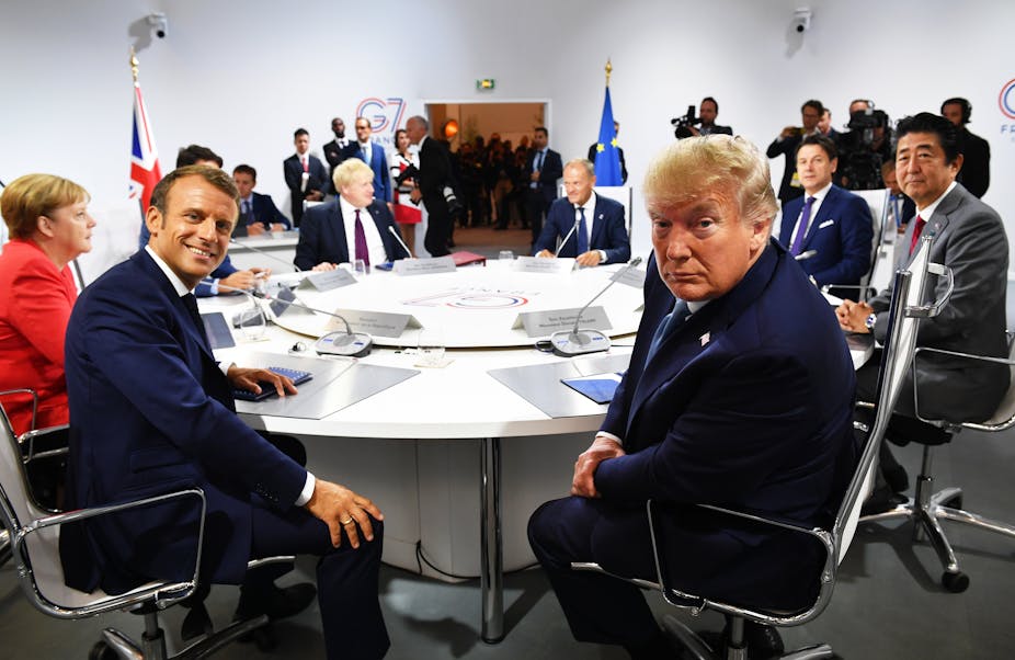 Emmanuel Macron and Donald Trump around a table with Angela Merkel Boris Johnson Donald Tusk Giuseppe Conte and Shinzo Abe. 