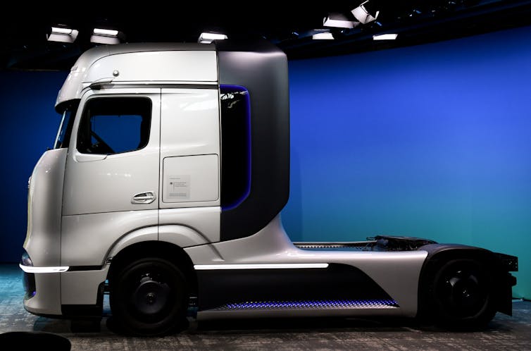A silver and black truck without a trailer on display in a well-lit showroom.