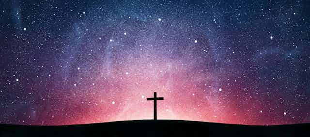 Picture of a wooden cross against a starry sky.