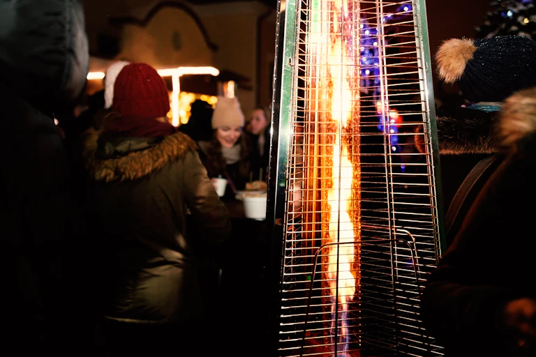 An outdoor heater with people socialising in background.