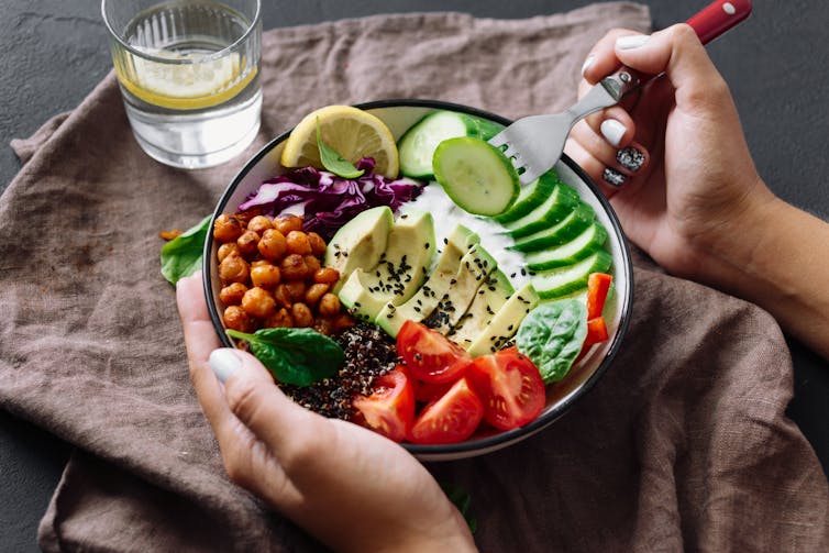 A bowl of healthy foods, including avocado, chickeas, and tomatoes.