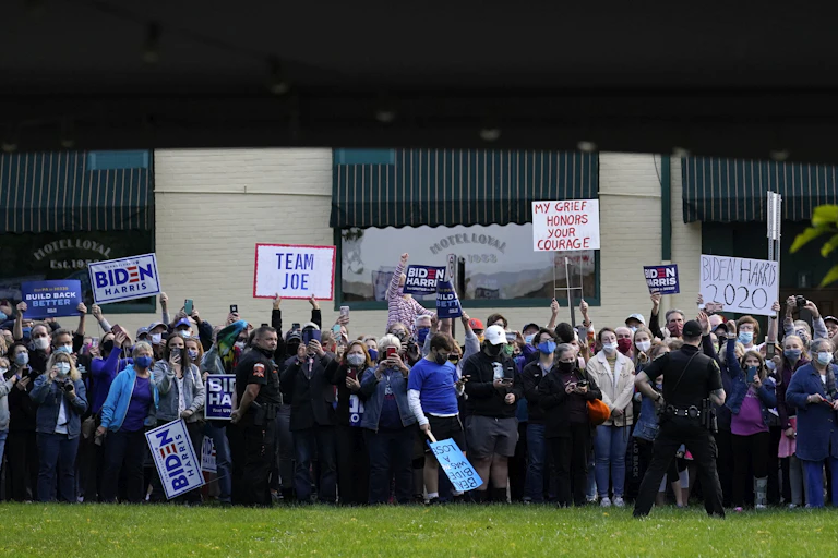 Group of people standing and holding Biden signs.