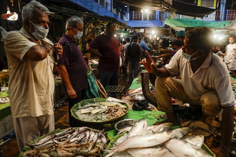 A man buying fish from another man at a market.