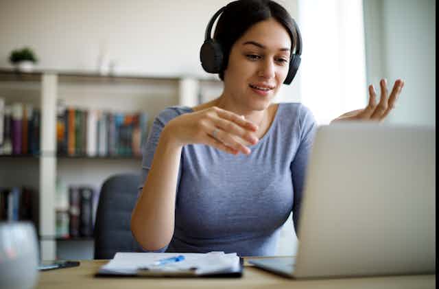 A woman uses a laptop while she is wearing headphones 