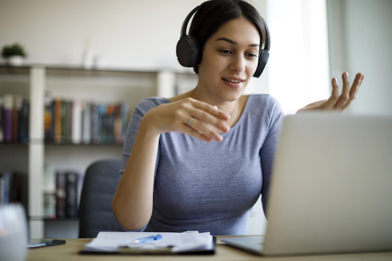 A woman uses a laptop while she is wearing headphones