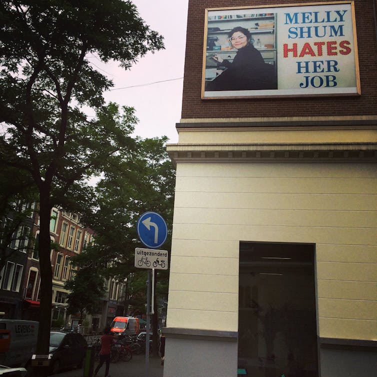 Woman in glasses shown on the outside of a building.