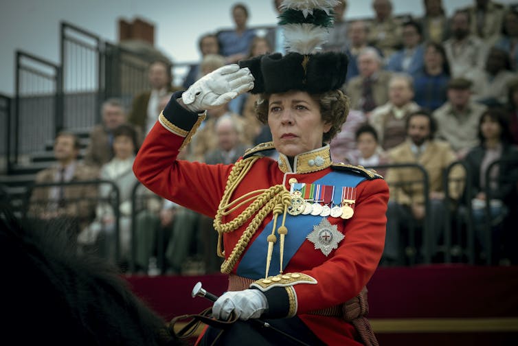 The Queen salutes while riding a horse
